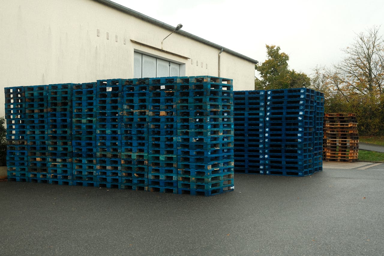 Massive stack of blue wooden pallets outside a building, ready for transport.